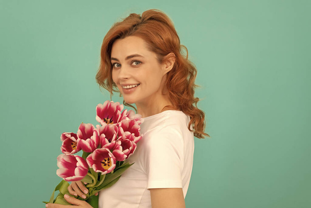 happy girl portrait with tulip flower bouquet on blue background. - Photo, Image