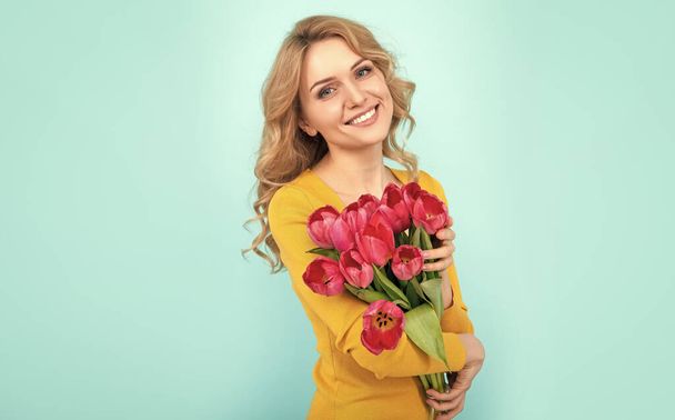 glückliches Mädchen mit Frühling Tulpenstrauß auf blauem Hintergrund. - Foto, Bild