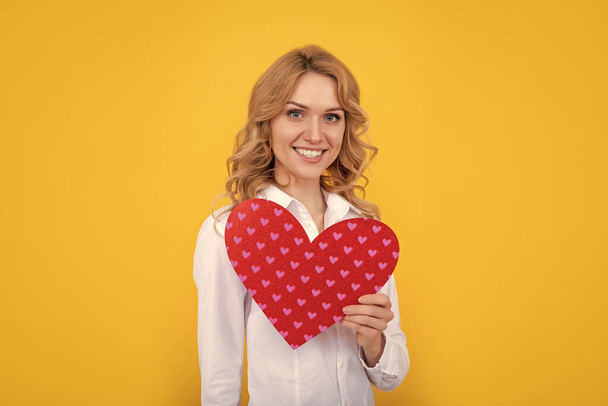 усміхнена жінка з червоним любов'ю серце на жовтому фоні
. - Фото, зображення