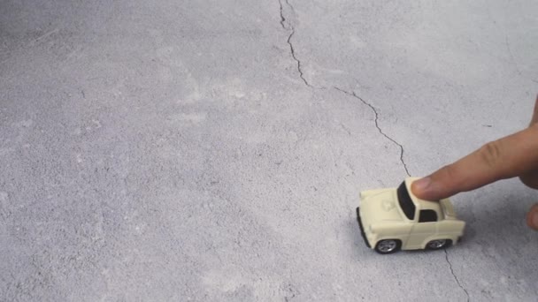 Finger rolls a toy car into shot playing with it on a concrete surface. Releases it. Car goes forward.Finger pushes a toy car forward, into the shot, plays with it. Nice copy space for your important messages - Materiał filmowy, wideo