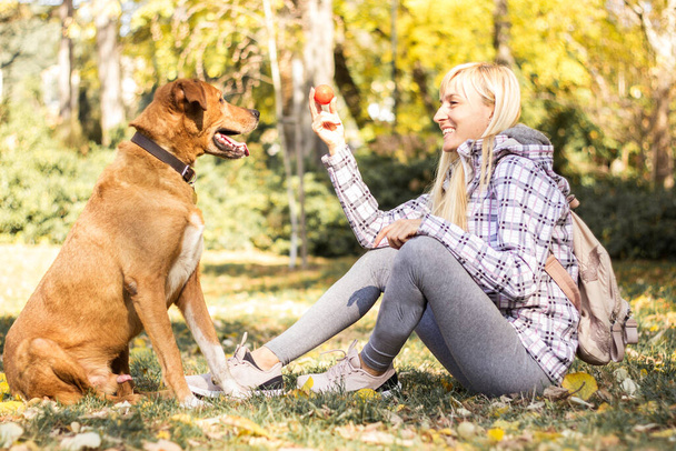 Happy young adult woman enjoys time at a park with her dog - Foto, imagen