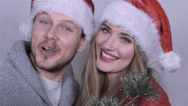 Happy beautiful Christmas couple singing carols over white background. - Video, Çekim
