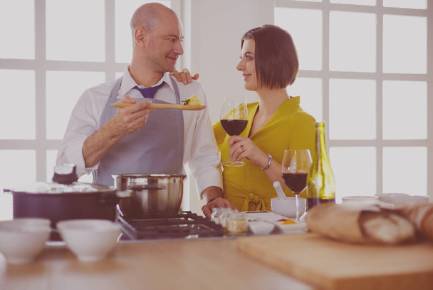 Attractive couple in love cooking and opens the wine in the kitchen while they cook dinner for a romantic evening. - Zdjęcie, obraz