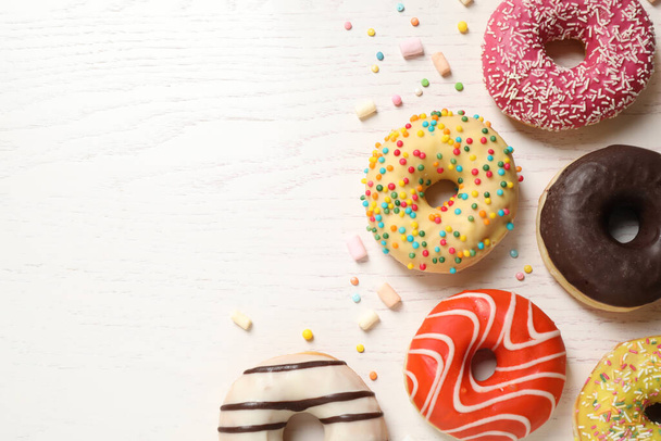 Delicious glazed donuts on white wooden table, flat lay. Space for text - Foto, Imagen