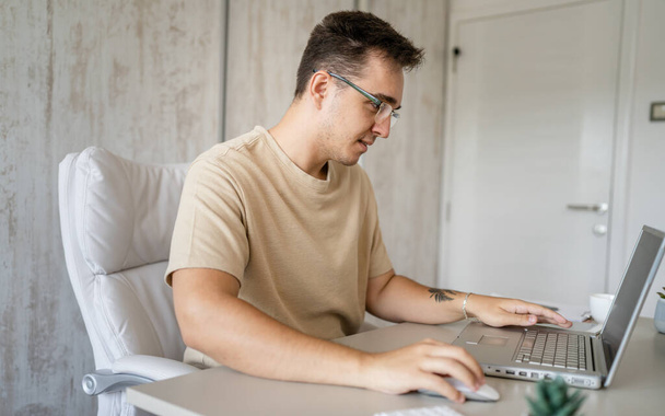 One caucasian man sitting at office at work working on laptop computer in day young freelance or entrepreneur businessman online business copy space young adult finishing or beginning confident happy - Photo, Image