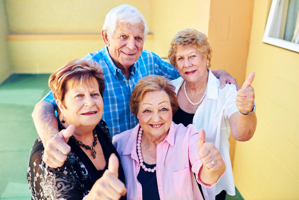 Έρχεται σε πολλές ακόμα περιπέτειες. μια ομάδα χαρούμενα ηλικιωμένα άτομα χαμογελώντας και ποζάροντας για την κάμερα έξω από ένα κτίριο - Φωτογραφία, εικόνα