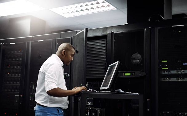 Skilled in all things IT. an IT technician using a computer while working in the server room of a data center - Photo, image