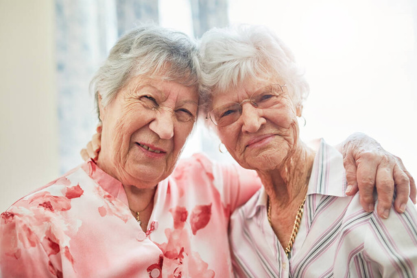Shes my golden girl. Portrait of two happy elderly women embracing each other at home - Foto, Imagem