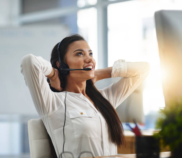 I like to relax after I solve a customers problem. a female agent working in a call centre - Foto, Imagem