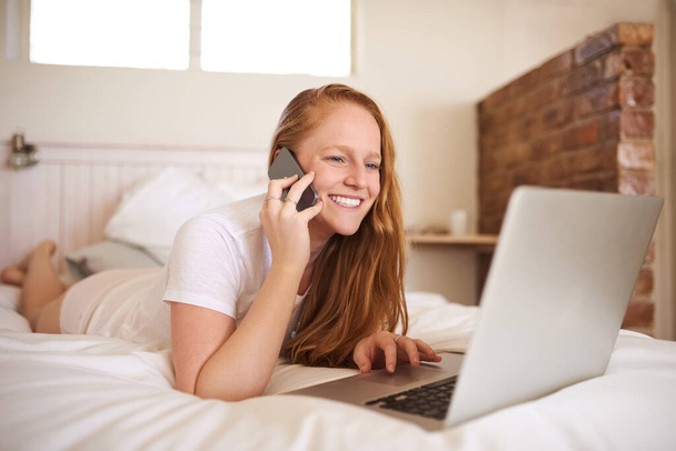 She loves blogging early in the morning. a young woman laying in bed at home - Foto, Imagen