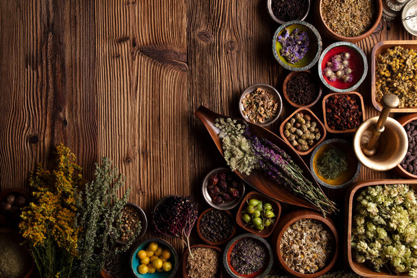 Natural medicine background. Assorted dry herbs in bowls, mortar and plants on rustic wooden table. - Φωτογραφία, εικόνα