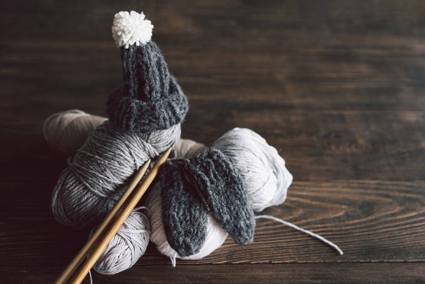 Balls of wool yarn, knitted little hat and wooden knitting needles on wooden background. Hobby craft. Concept of knitting, needlework. - Fotoğraf, Görsel