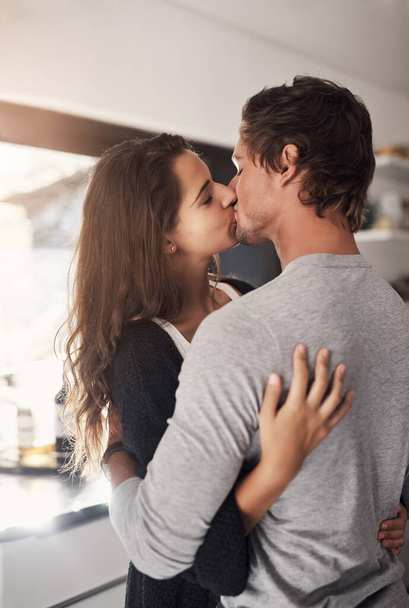 Все відчувається так правильно, коли ми цілуємося. лагідна молода пара цілується на кухні вдома
 - Фото, зображення