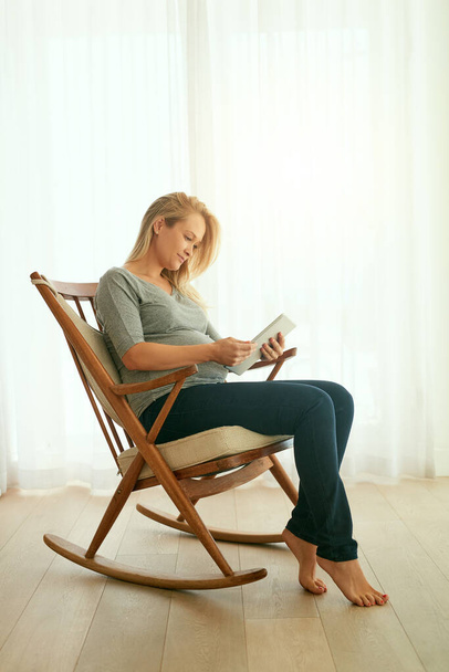 У мене є своя особиста група підтримки тут. вагітна жінка використовує свій цифровий планшет, сидячи на кріслі для камінгу
 - Фото, зображення