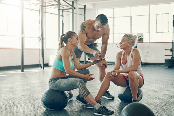 We could definitely incorporate this tutorial in our workout routine. a group of young people using a digital tablet at the gym - Foto, immagini