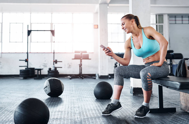 Checking where her gym buddies are. a woman using a cellphone in a gym - Foto, Imagem
