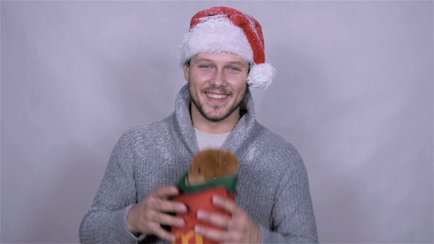 Happy man in Santa Claus hat with christmas gift. Slow motion. - Imágenes, Vídeo