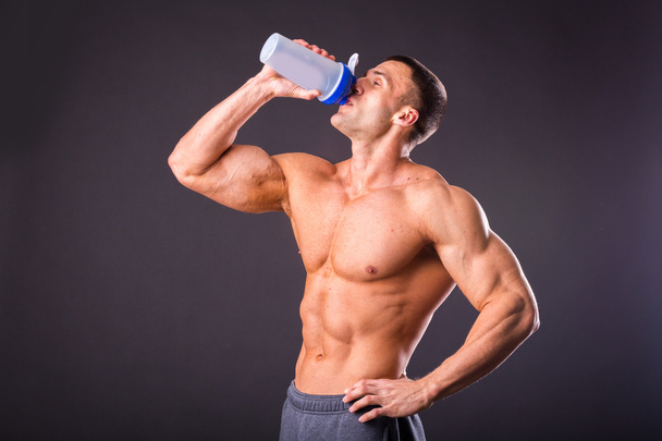 Bodybuilder holding a shaker for drinks - Фото, изображение