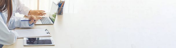 Баннер двух азиатских женщин-докторов, обсуждающих совместную работу медицинской команды. Панорама Две азиатки-врачи встречаются в офисе медицинской клиники с помощью ноутбука обсуждения пациента с копировальным пространством. - Фото, изображение