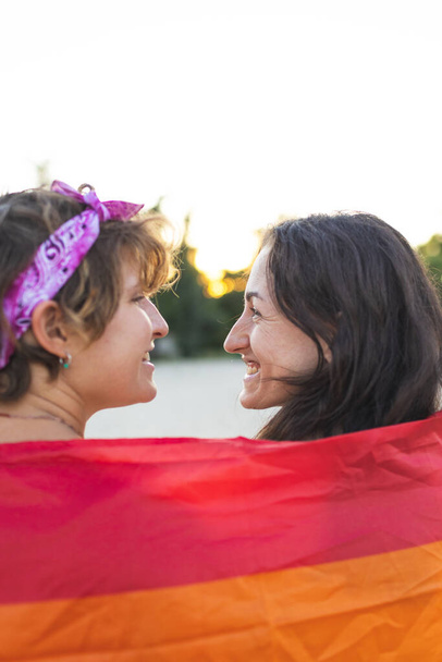 fiatal leszbikus pár ölel gyengéden. Szivárvány zászló az utcán. egyenlő jogok az lgbt közösségnek, intimitás és érzések két lány iránt - Fotó, kép
