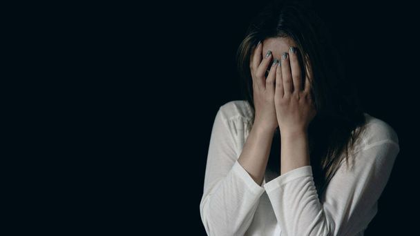 Young person woman sad, stress and loneliness sitting in dark room, Unhappy and crying teenage girl from domestic violence, An adult female expresses feelings of despair, anxiety from harassment. - Foto, Bild