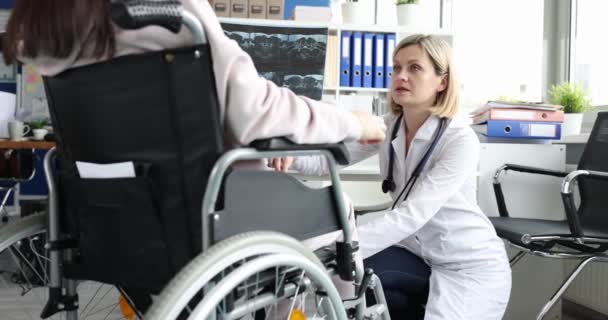 Невролог бьет человека в инвалидном кресле с молотком на коленях крупным планом. Проверка рефлексов после травмы - Кадры, видео