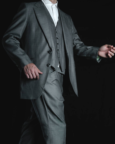 Unrecognizable businessman dressed in a gray colored suit. Elegant gray suit. An elegant man on black background. High quality photo - Foto, Imagem