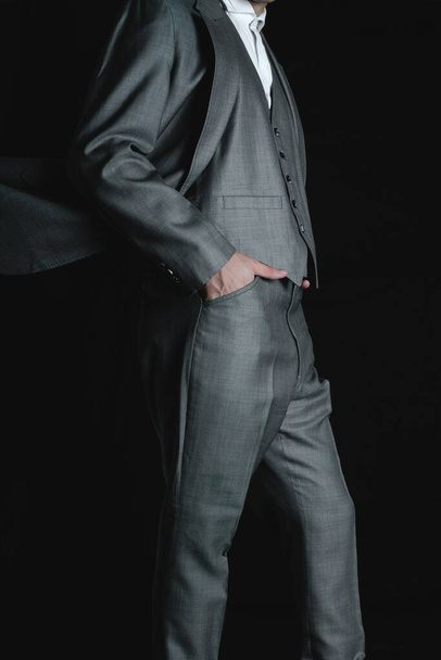 Businessman with his hands on the bag. Gray suit with jacket and pants. Elegant man modeling a gray colored jacket. High quality photo - Fotó, kép