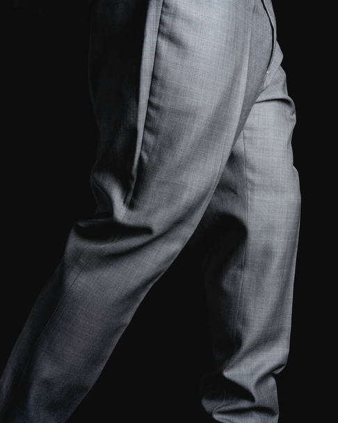 Gray pants on a black background. Fine fabric texture. Elegant suit pants. High quality photo - Zdjęcie, obraz
