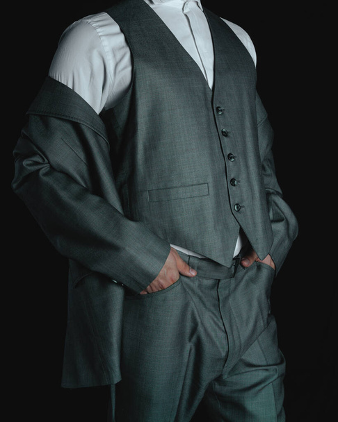 Body of a man in a gray suit. Elegant gray suit. Business man posing on a dark colored background. Man dressed in suit modeling his suit. High quality photo - Foto, Imagem