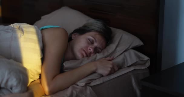 A sunbeam wakes up a beautiful sleeping woman, close-up. Cozy comfortable bedroom, soft bed, joyful awakening - Filmati, video