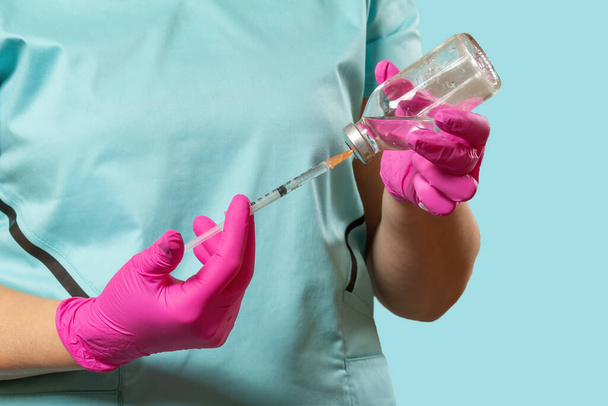 Glass bottle for liquid medicine and a plastic syringe for injection in hands in latex gloves. - Photo, Image