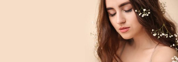 Beautiful young woman with flowers in her hair on beige background with space for text - Fotoğraf, Görsel