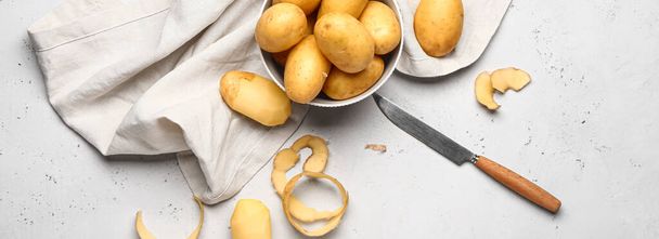 Bowl with fresh potatoes and knife on light background, top view - Foto, Imagen