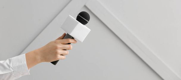 Journalist's hand with microphone on grey background - Photo, Image