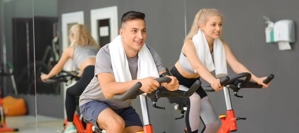 Young people training on exercise bikes in gym - Photo, Image
