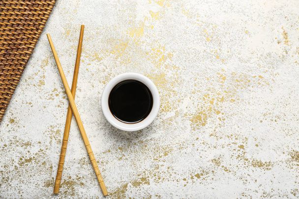 Bowl of soy sauce, chopsticks and mat on grunge background - Foto, Bild