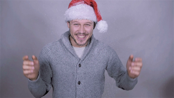 Красивий чоловік у капелюсі Санта Клауса насолоджується снігом, повільним рухом
. - Кадри, відео