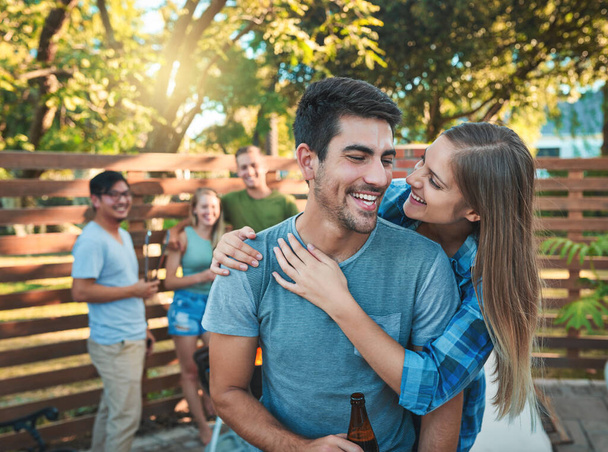 Just checking in with my favourite guy. an affectionate young couple enjoying themselves at a barbecue with friends - Photo, Image