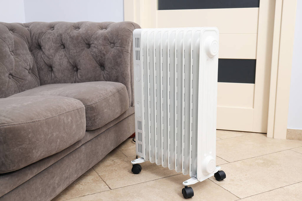 Concept of heating season, modern electric heater near sofa - Zdjęcie, obraz