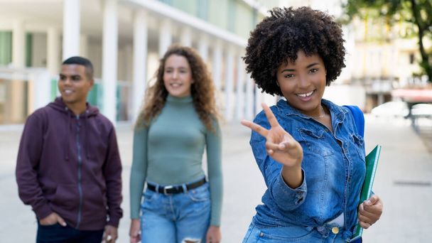 Happy african american female student with backpack and group of international students outdoor in summer in city - 写真・画像