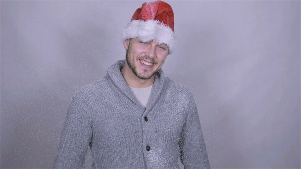 Красивий чоловік у капелюсі Санта Клауса насолоджується снігом, повільним рухом
. - Кадри, відео