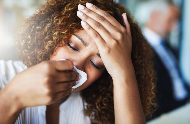 Yes I definitely have a fever. Closeup of a frustrated businesswoman using a tissue to wipe her nose while being seated in the office - Foto, Imagen