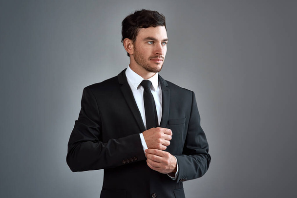 Ντύσου με σκοπό. Στιγμιότυπο ενός όμορφου νεαρού επιχειρηματία ντυμένου με κοστούμι σε γκρι φόντο - Φωτογραφία, εικόνα