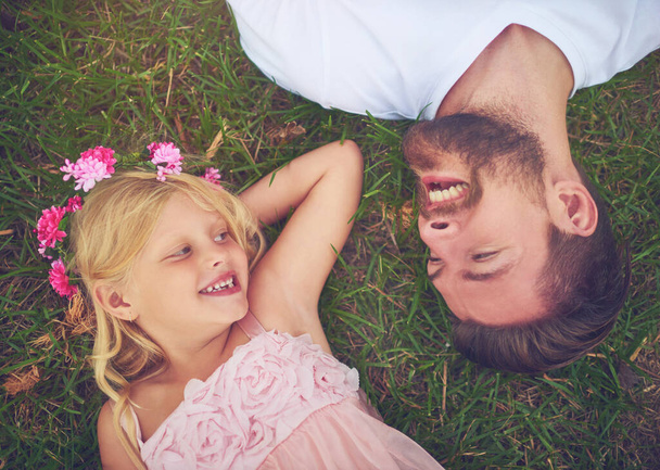 Her dad is her best friend. a happy daughter and father lying on the ground looking at one another outside in nature - Foto, immagini
