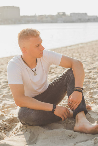 Young guy at beach in tranquility mood, rest in vacation. Summer portrait of handsome men at beach, concept of vacation, rest time  - Valokuva, kuva