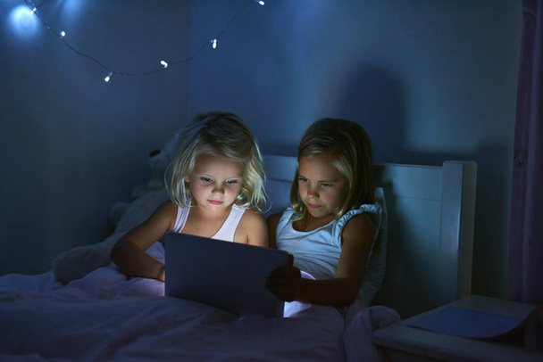 Терези завжди щось, щоб тримати їх розважальними в Інтернеті. дві маленькі дівчата використовують цифровий планшет перед сном
 - Фото, зображення