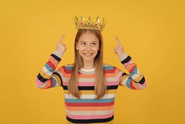 happy teen kid point finger on queen crown on yellow background. - Photo, Image