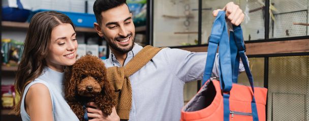 Muslim man holding animal dog near girlfriend with poodle in store, banner  - Fotografie, Obrázek