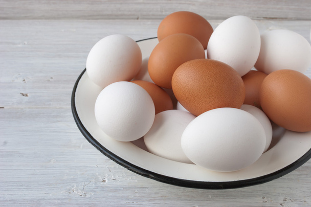 Chicken eggs in a metall dish on the white boards - Foto, afbeelding